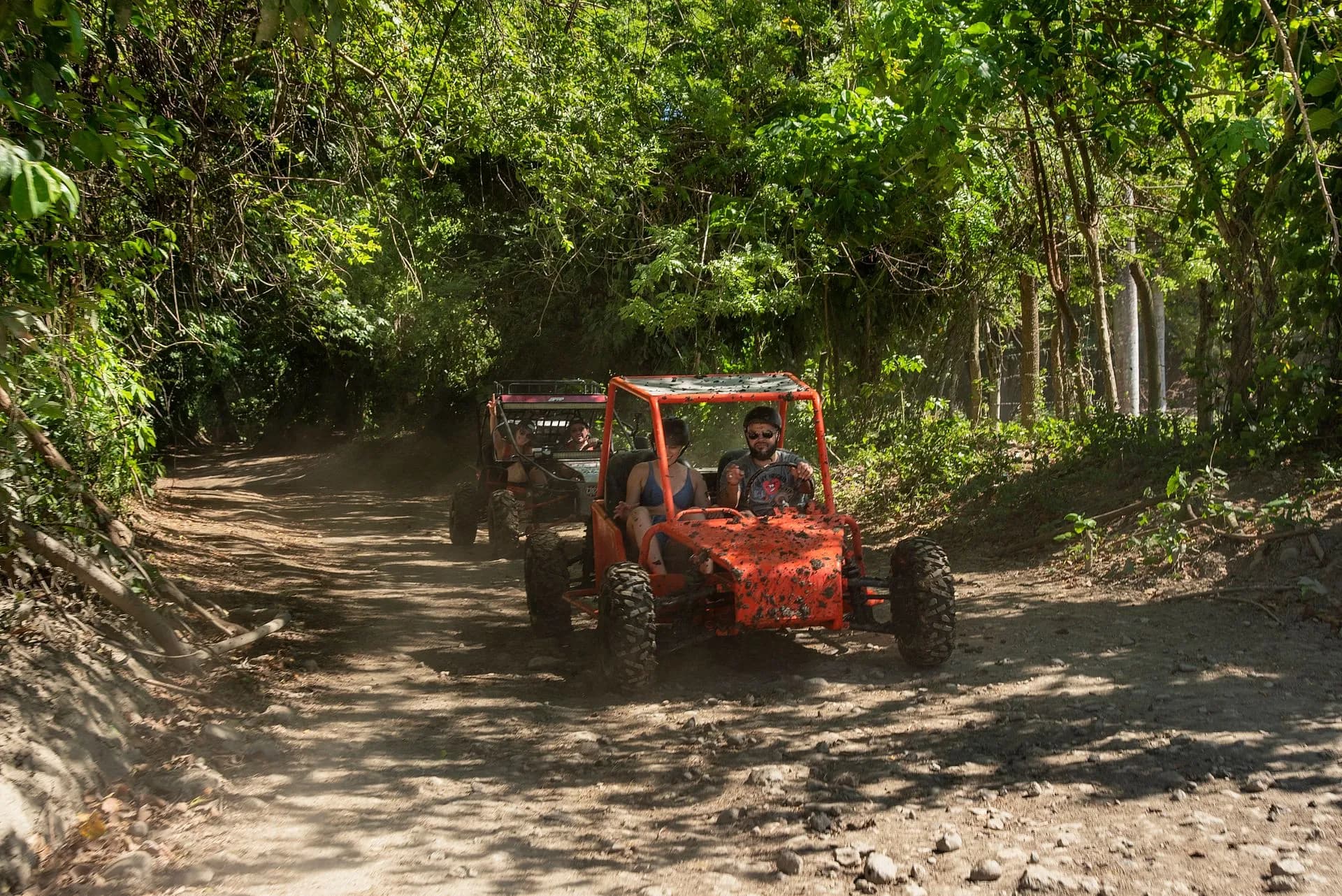 Rider splashing a buggy through a muddy red-dirt trail near Macao Beach in Punta Cana