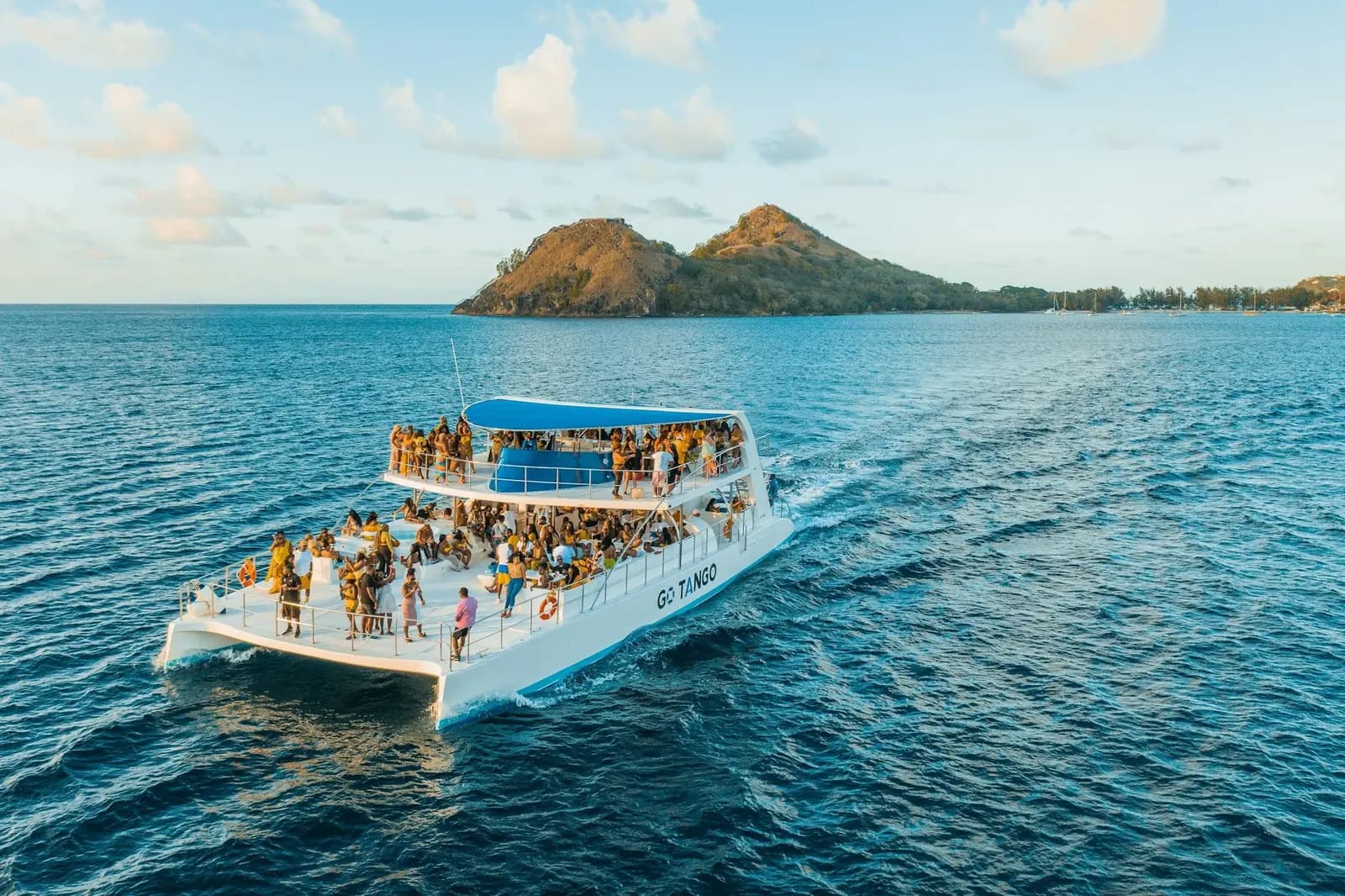 Guests dancing on the deck of a catamaran party boat off the coast of Punta Cana at golden hour